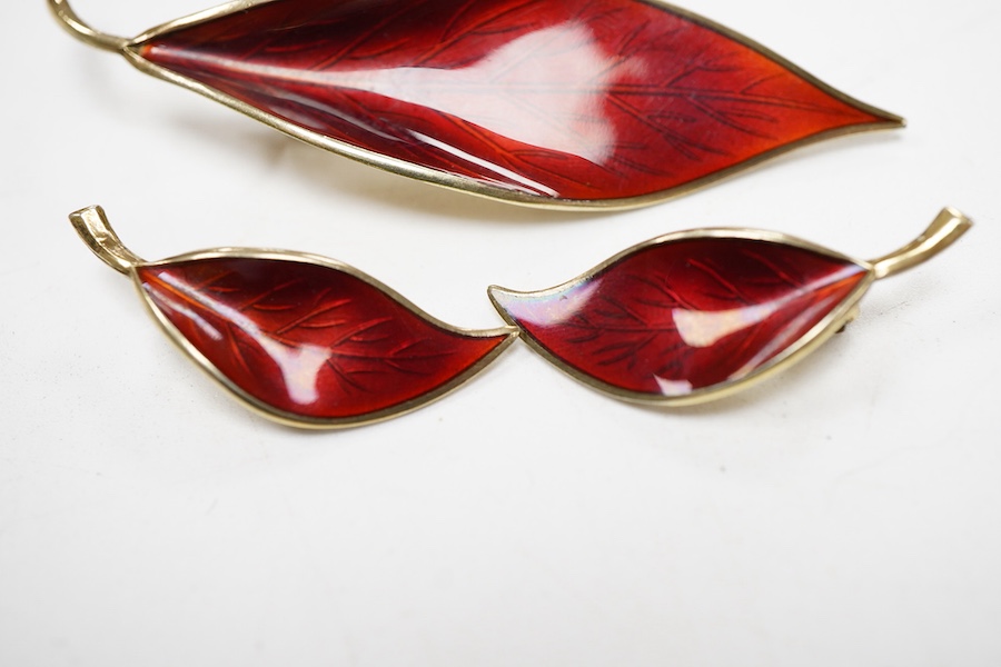A Norwegian gilt white metal and red enamel demi parure, by David Andersen, comprising a leaf shaped brooch, 65mm and a pair of matching ear clips.
